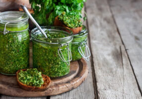 Homemade cilantro pesto in jars on wooden background